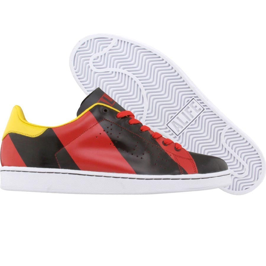 Low top sneaker with bold red and black stripes and a yellow heel.